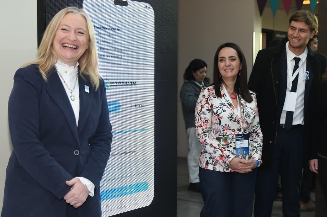 Two organisers next to a screen showing the event portal on a phone; one wears the credential carrying the QR code