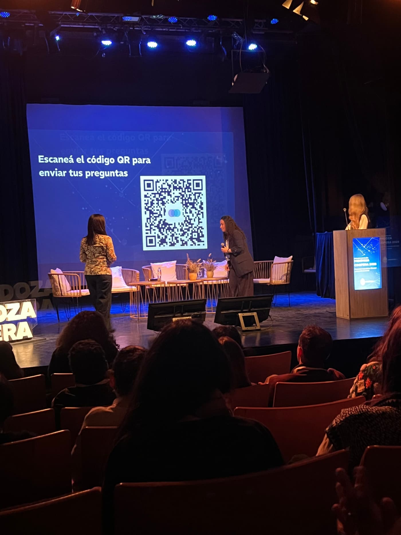 Stage screen showing a large QR code and the text scan the QR code to send your questions, during a panel